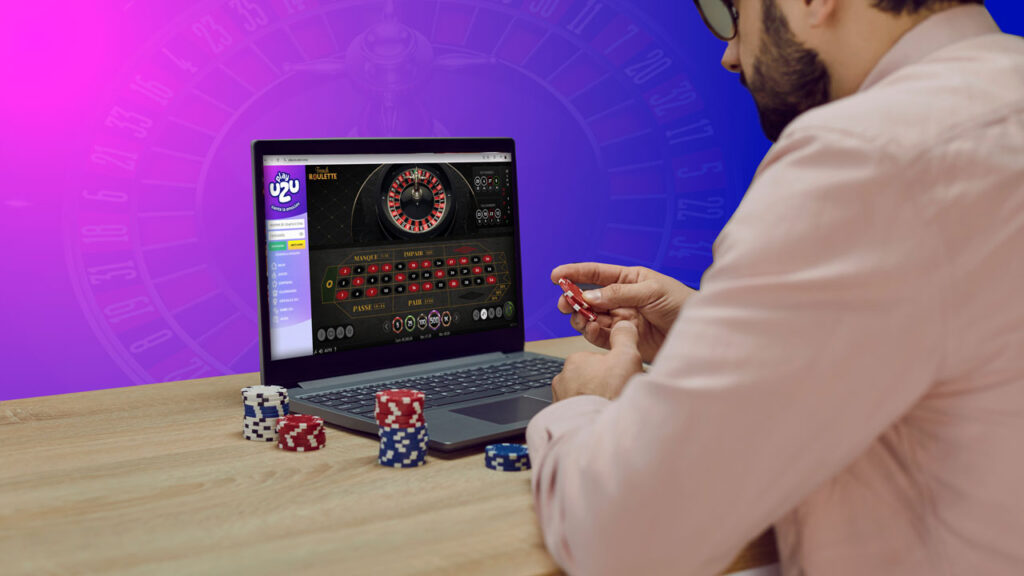 Apostador experimentado aplicando estrategias más efectivas para la ruleta online, sosteniendo fichas mientras observa la ruleta girar en su ordenador portátil. 